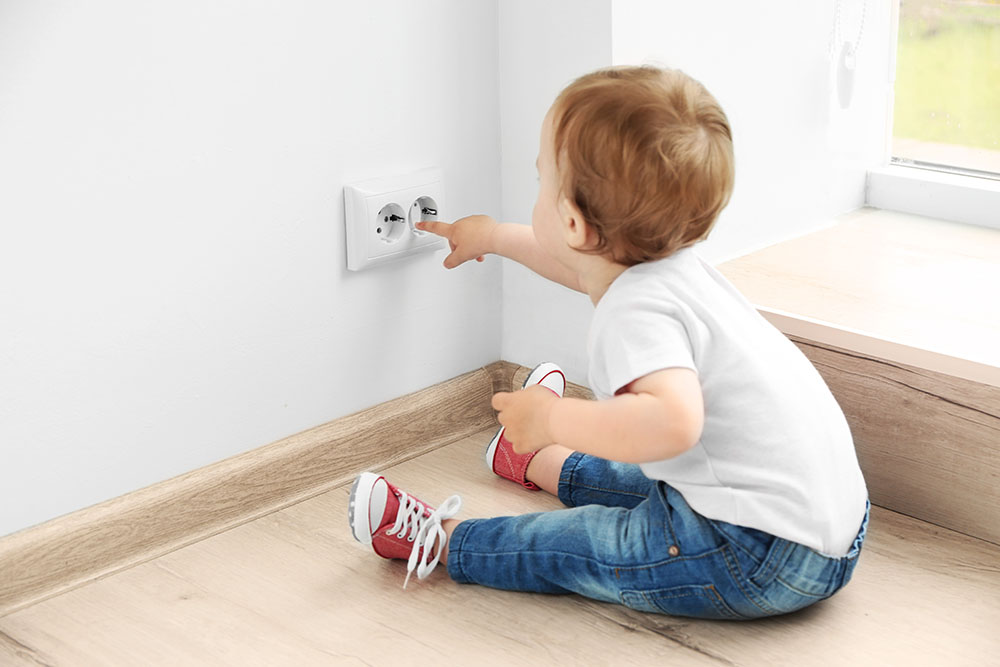 Baby playing with electrical outlet on floor at home