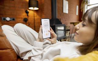 Liegende Frau blickt zufrieden auf ihre Smart Home App