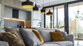 Dimmbare 230 Volt Deckenlampen neben eine Couch mit Kissen und einer gelb-schwarzen Pendelleuchte
