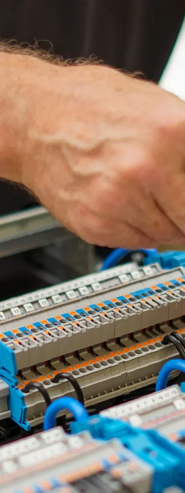 Auf dem Bild ist zu sehene, wie eine Fachperson einen Verteilerschrank zusammenbaut.